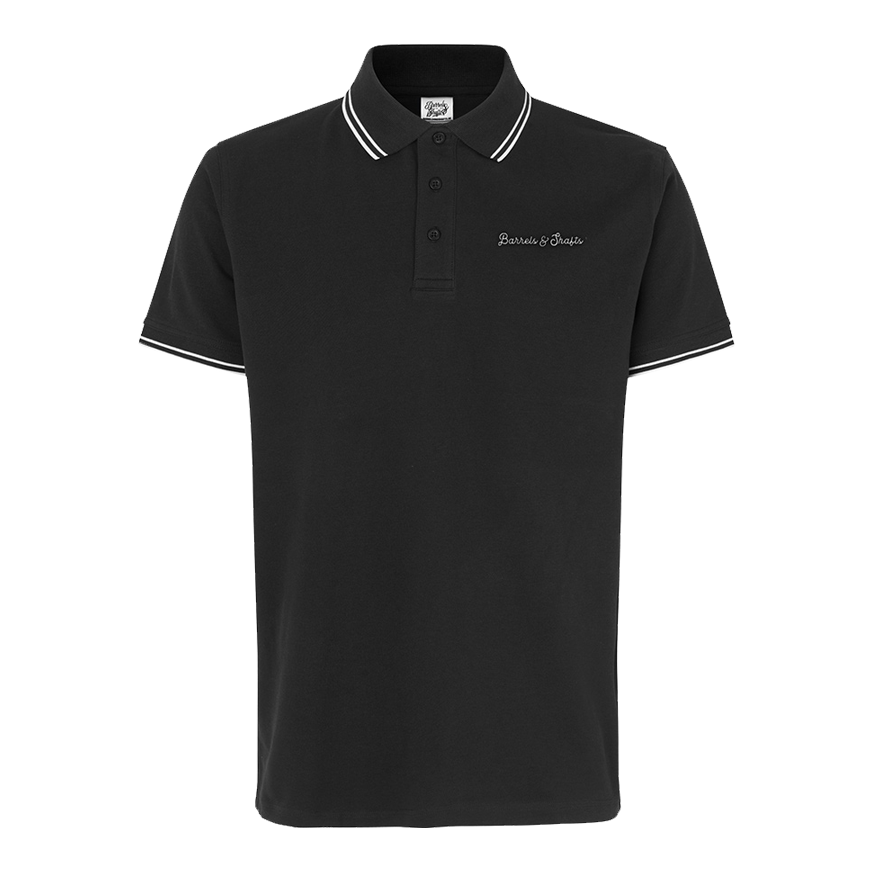 Vaten en schachten poloshirt - zwart Das Bild zeigt ein schwarzes Poloshirt mit weißen Akzenten an Kragen und Ärmeln. Auf der Brust ist der Schriftzug "Barrels & Shafts" eingestickt.