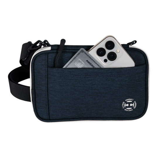 Harrows Smart Case XL dart portemonnee Eine blaue Tasche mit Vorderfach enthält ein Smartphone und eine Kreditkarte. Am unteren Rand der Tasche befindet sich ein rundes weißes Logo.