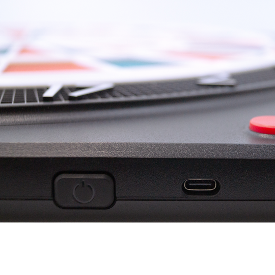 Karella CB-Smart Elektronisch Zacht Dartbord Das Bild zeigt einen Ausschnitt der Karella CB-Smart Elektronische Soft-Dartscheibe. Zu sehen sind der Ein-/Ausschalter und ein USB-C Anschluss an der Seite des Geräts.