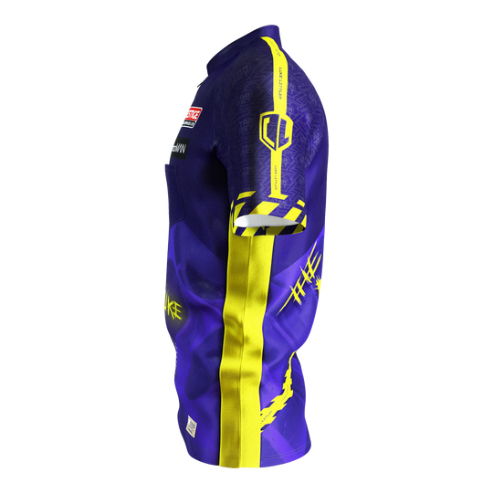 Target Coolplay Luke Littler 2025 dartshirt Das Bild zeigt ein Dartshirt in lila und gelb mit auffälligem Design. Auf dem Ärmel steht "LUKE LITTLER" und es sind verschiedene grafische Elemente abgebildet.