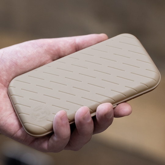 Harrows Slimcase Dart Case Eine Hand hält ein schlankes, steingraues Etui mit einem dezenten Muster. Das Etui wirkt stabil und ist wahrscheinlich für Dartzubehör gedacht.