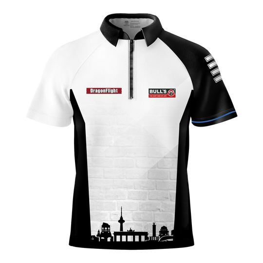 Bulls Martin Schindler The Wall dartshirt Das Bild zeigt das Bulls Martin Schindler The Wall Dartshirt mit einem schwarz-weißen Design und kurzen Ärmeln. Auf der Vorderseite befinden sich Logos und eine stilisierte Stadtsilhouette am unteren Rand.