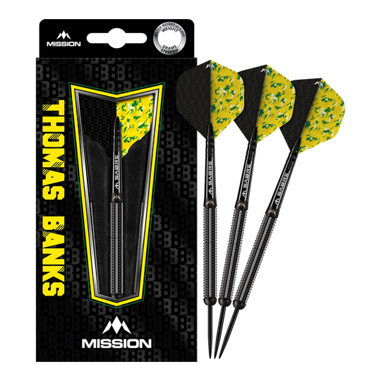 Das Bild zeigt die "Mission Thomas Banks Black PVD Steeldarts - 24g" in ihrer Verpackung. Drei schwarze Steeldarts mit gelb-grünen Flights sind neben der Verpackung sichtbar.