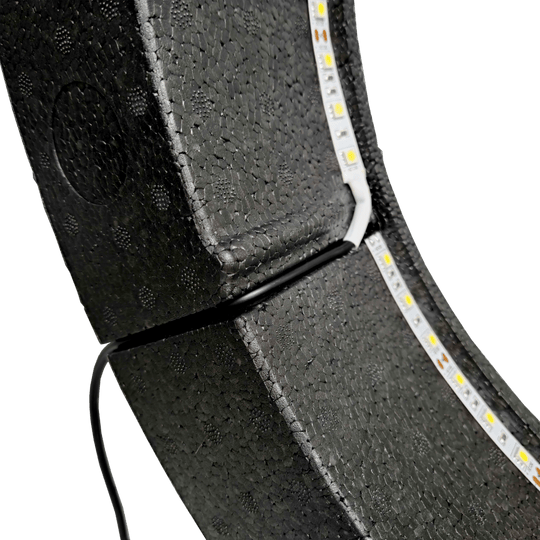 Bulls NL Lumo Light Surround verlichtingssysteem Das Bild zeigt das „Bulls NL Lumo Light Surround Beleuchtungssystem“ mit LED-Leuchtstreifen auf einer schwarzen, strukturierten Oberfläche. Ein Kabel ist ebenfalls an das Beleuchtungssystem angeschlossen.