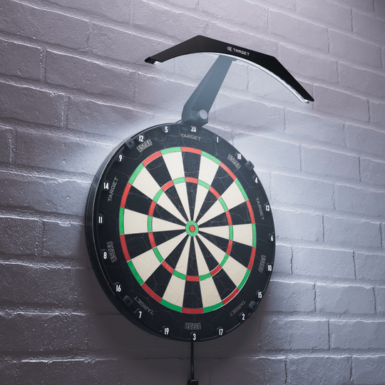 Target ARC V2 Dartbordverlichting Das Bild zeigt eine Dartboard-Beleuchtung namens "Target ARC V2", die über einem Dartboard an der Wand montiert ist. Das Licht leuchtet das Dartboard gleichmäßig aus und sorgt für eine klare Sicht auf die Felder.